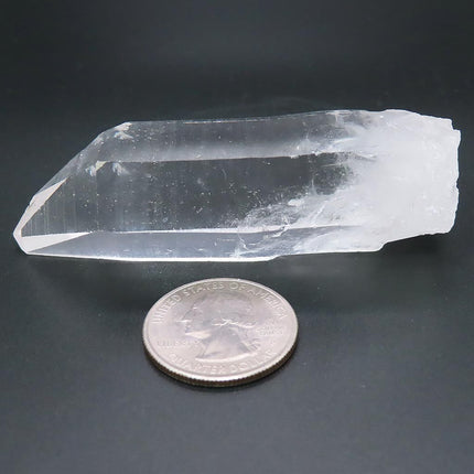 Arkansas Quartz Crystal Point with Time-Link Activation next to a U.S. quarter on a dark background