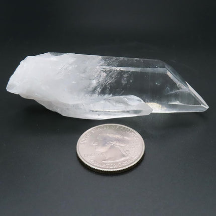 Arkansas Quartz Crystal Point with Time-Link Activation next to a U.S. quarter on a dark background