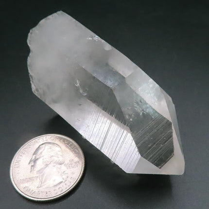 Arkansas Quartz Crystal Point with Window & Self-Healed Base next to a quarter on a dark background