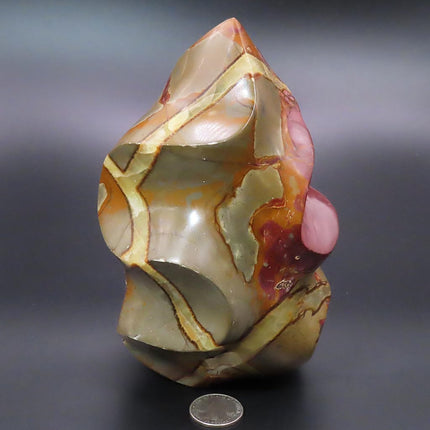 Large Polished Septarian Nodule Flame Carving from Madagascar
with a coin for scale on a dark background