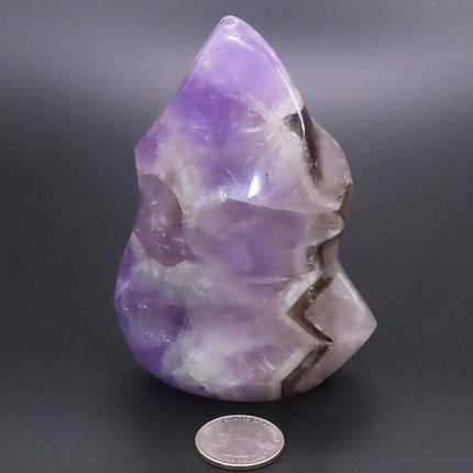 Polished Smoky Amethyst Flame Carving from Madagascar with a coin for scale on a dark background