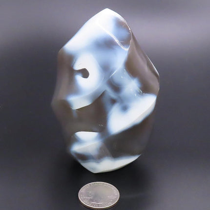 Polished Snow Blue Agate Flame Carving from Madagascar on a dark background with a quarter for scale