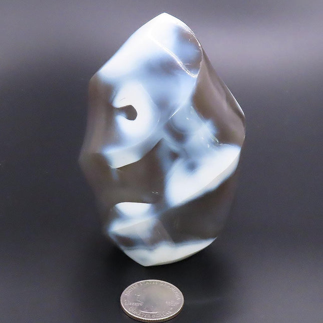 Polished Snow Blue Agate Flame Carving from Madagascar on a dark background with a quarter for scale