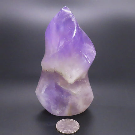 Polished Smoky Amethyst Flame Carving from Madagascar with a quarter for scale on a dark background