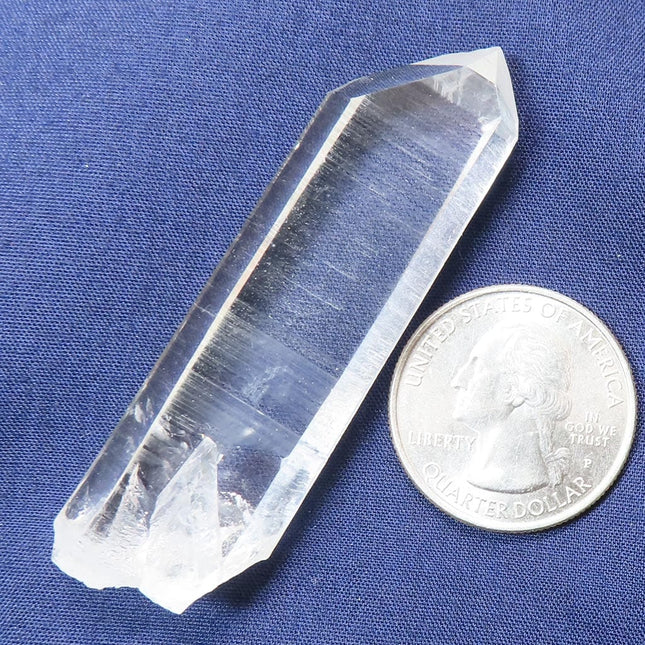 Arkansas Quartz Crystal Tabby Point with Record Keeper Triangles next to a quarter on a blue background