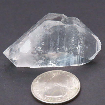 Arkansas Quartz Crystal Double Terminated/ET Point next to a U.S. quarter for scale on a dark background