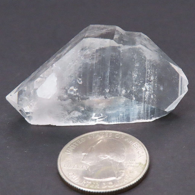 Arkansas Quartz Crystal Double Terminated/ET Point next to a U.S. quarter for scale on a dark background